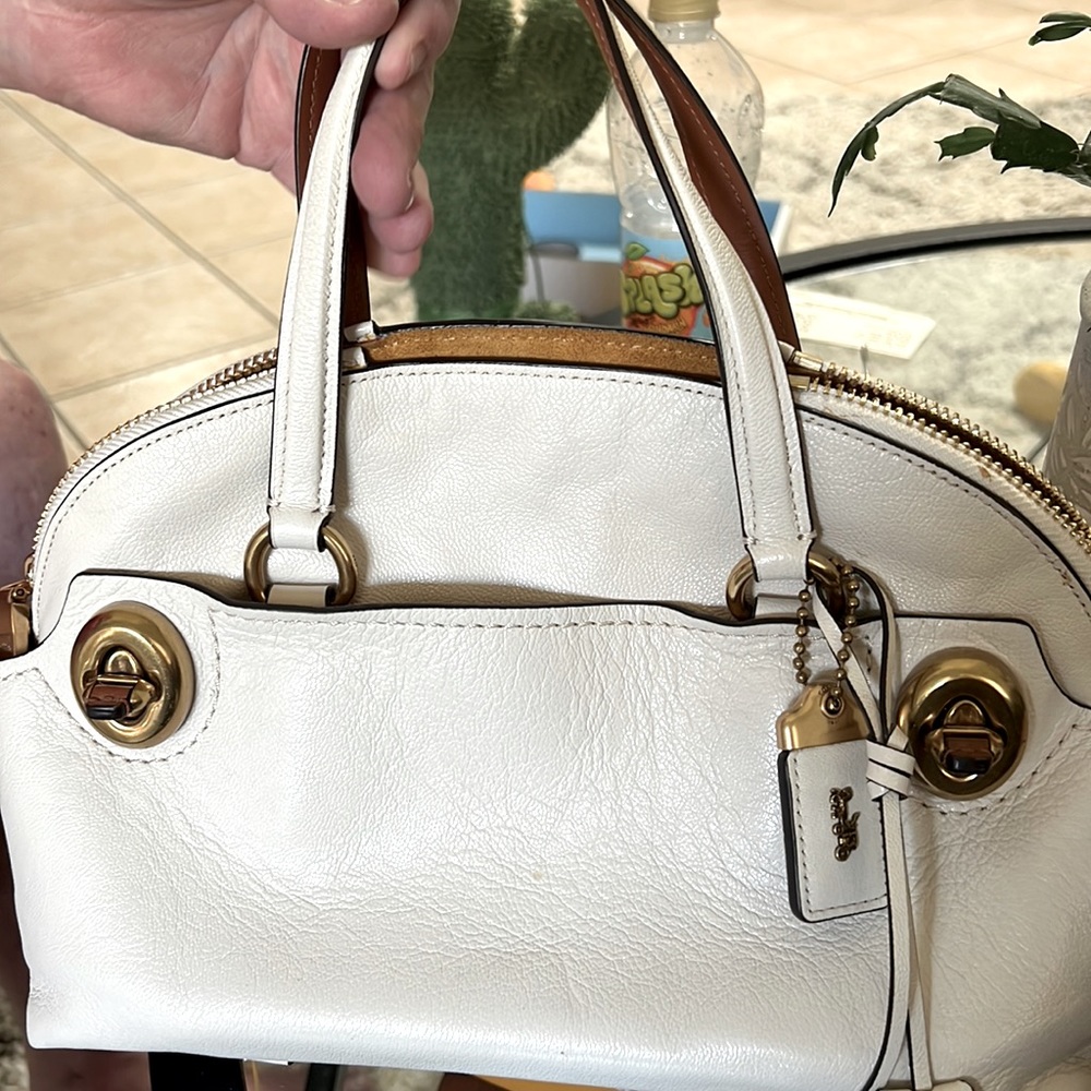 Ivory Coach bag with two exterior pockets and two inside pockets. Gold hardware.